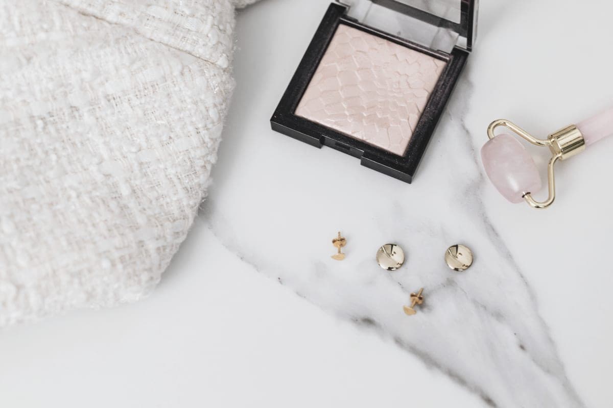 Small gold stud earrings arranged on a pale stone surface