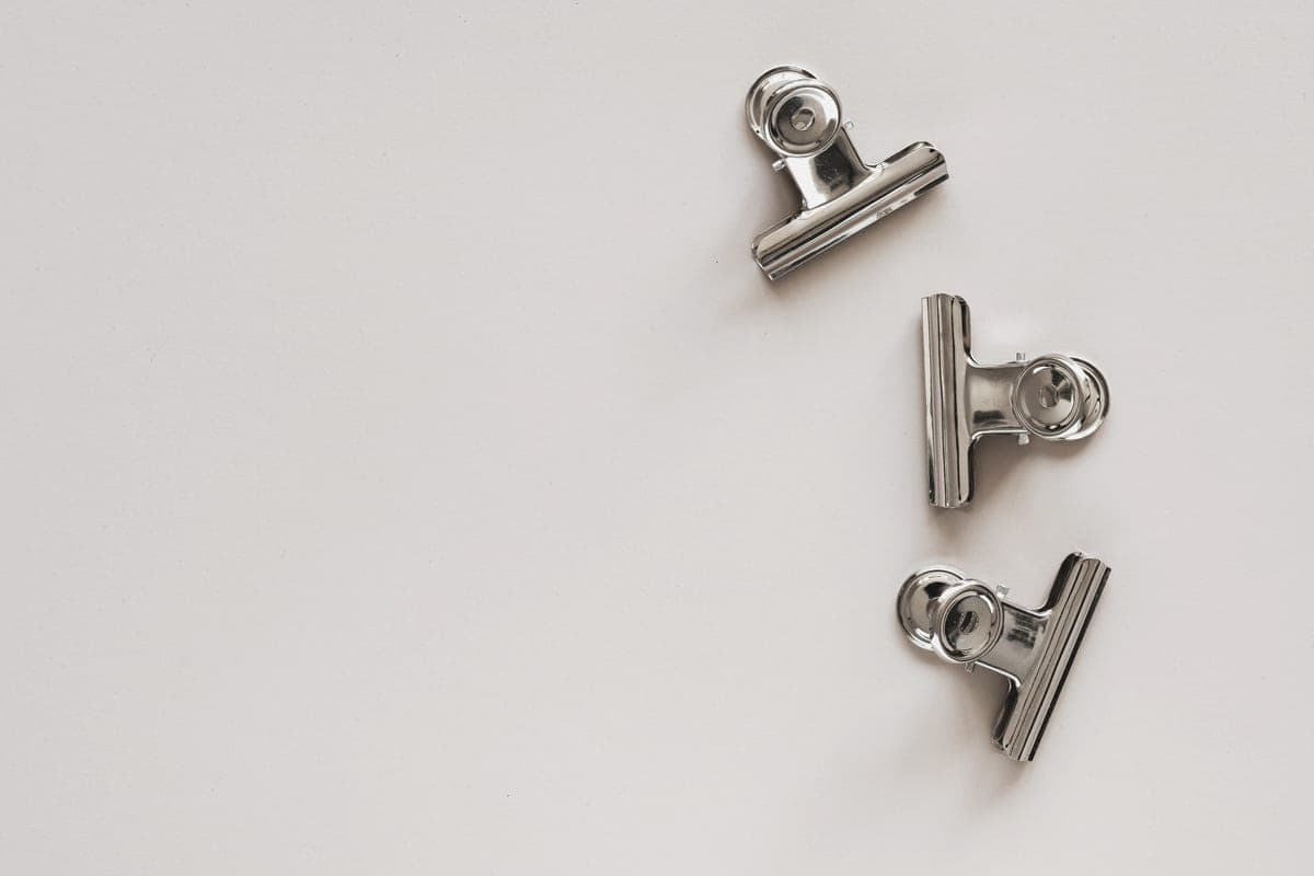 Small plain silver-toned earrings on a pale background