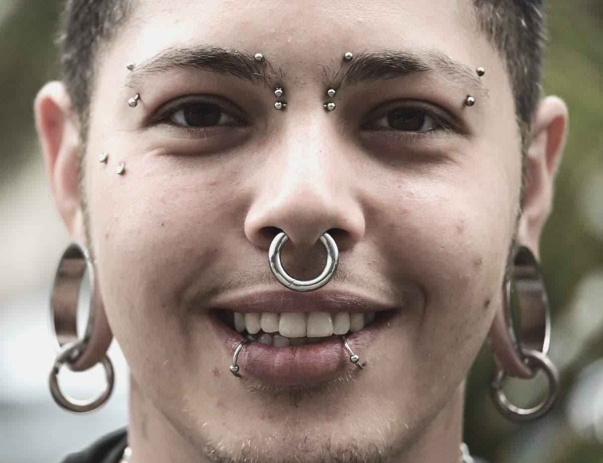 An ear wearing several small cartilage earrings, photographed in daylight
