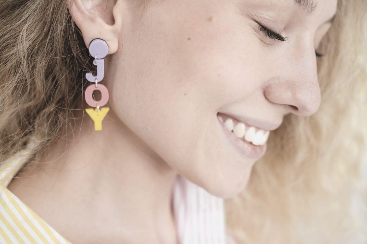 A close-up of a drop earring worn at the ear, photographed in soft daylight