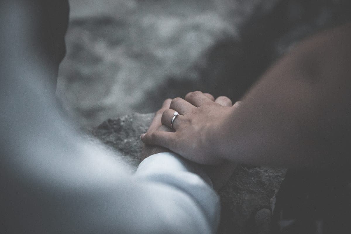 Two hands together outdoors, one wearing an engagement ring
