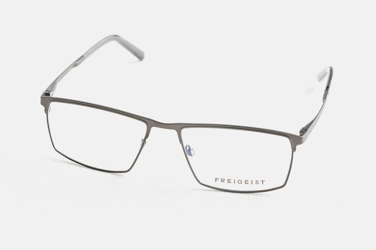 Thin metal eyeglasses folded on a plain, light surface