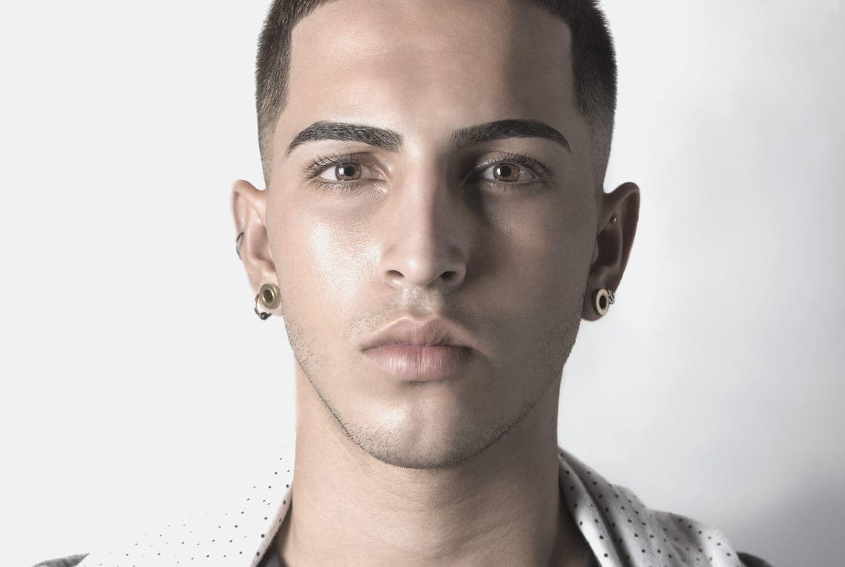 A person wearing a small silver-toned stud earring, photographed in daylight