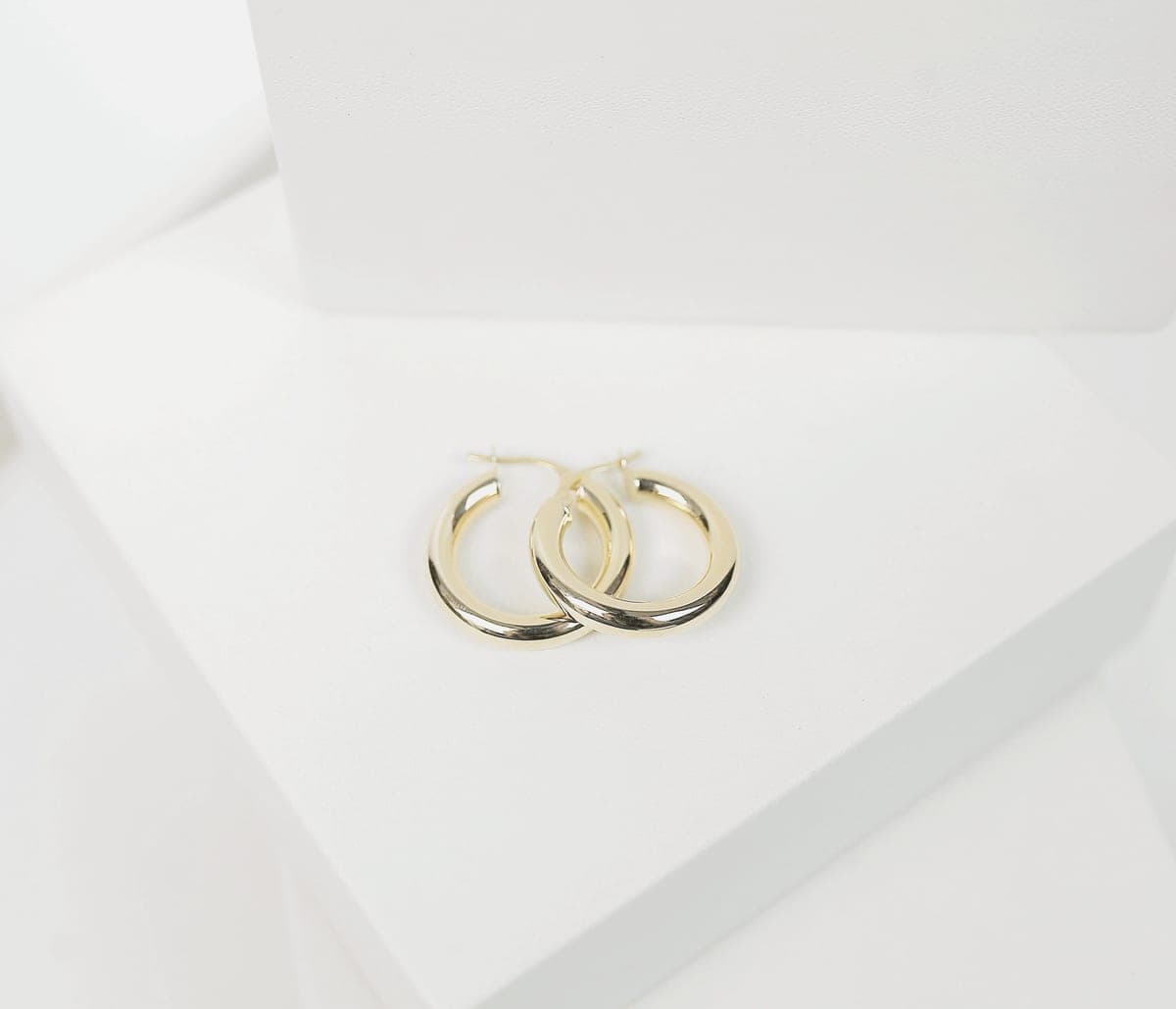 Thin gold hoop earrings photographed close up in soft light
