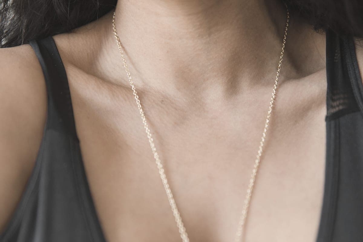 A fine gold chain resting on a collarbone in soft light