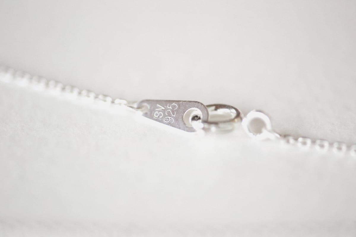 Silver-toned jewelry resting on soft white cloth in daylight