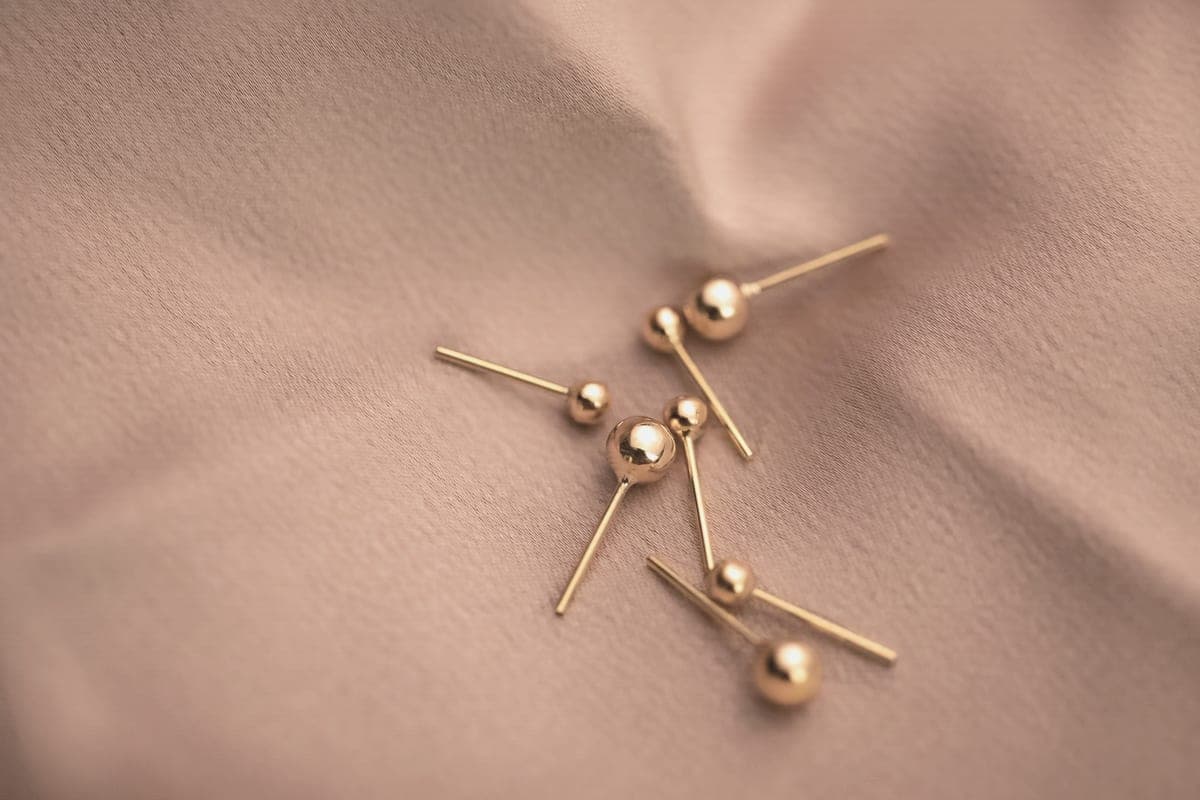 Small pearl stud earrings resting on cream-colored fabric