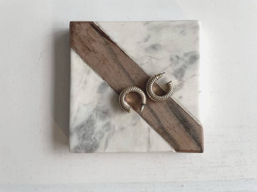 Thin gold hoop earrings resting on a pale marble surface