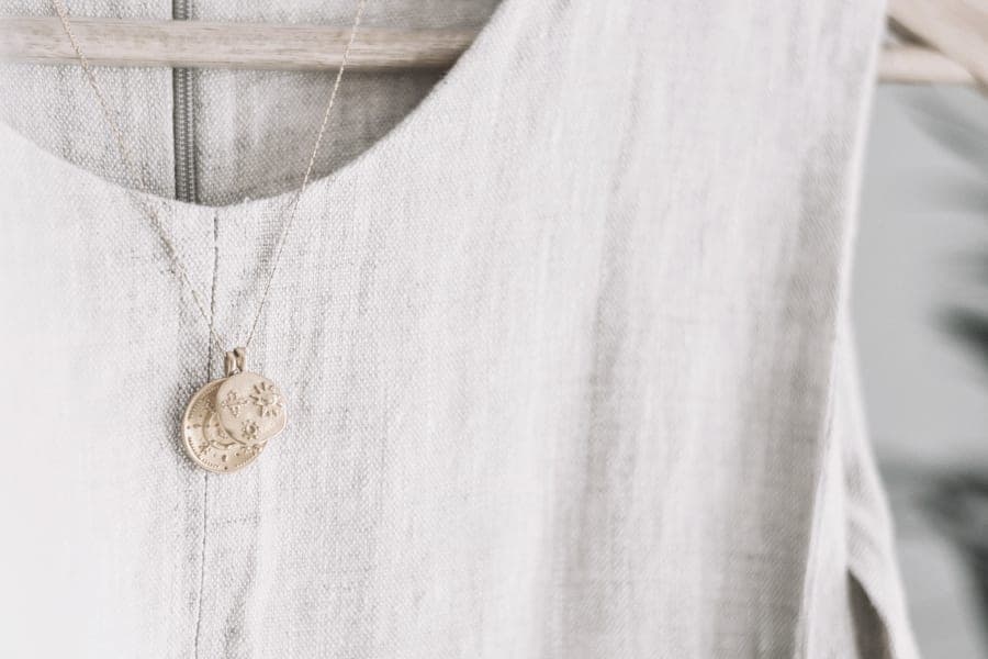 A fine gold chain necklace laid on a fold of beige linen